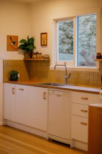 a kitchen with white cabinets and a sink and a window at Georgie Bay St Helens in St Helens +25 photos