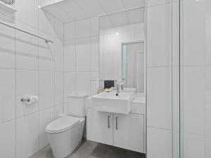 a white bathroom with a toilet and a sink at Esplanade Escape in Indented Head +7 photos
