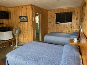 a bedroom with two beds and a fan and a television at Chicken Shack Motel in Batchawana
