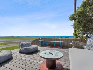 a wooden deck with a table and chairs and a bench at Esplanade Escape in Indented Head