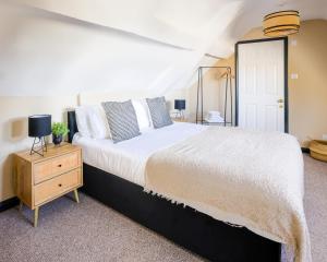 a bedroom with a large white bed and a wooden dresser at 5 bed central home- beautiful modern in Witney