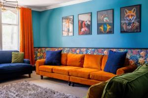 an orange couch in a living room with blue walls at 5 bed central home- beautiful modern in Witney