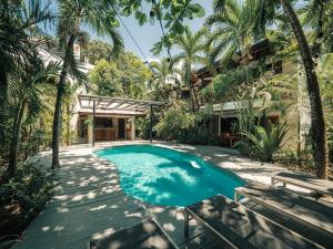 a swimming pool in a yard with palm trees at Beach Heaven in Playa Guiones