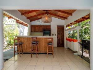 a kitchen with a bar with three stools at Beach Heaven in Playa Guiones