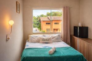 a bed in a room with a large window at Quarto tranquilo e confortável dentro de residência particular, 3 km do Aeroporto , 1,5 km da Praia in Navegantes