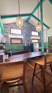 a large wooden table with two chairs and two lights at La Bima Beach House in Sekongkang Bawa