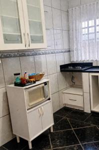 a small kitchen with a microwave on a counter at Recanto Sossego Wi-Fi 3 quartos 3 banheiros 2 chuveiros Espaço amplo churrasqueira in Espirito Santo Do Pinhal