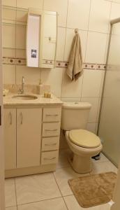 a white bathroom with a toilet and a sink at Recanto Sossego Wi-Fi 3 quartos 3 banheiros 2 chuveiros Espaço amplo churrasqueira in Espirito Santo Do Pinhal