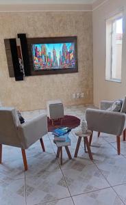 a living room with couches and a tv on the wall at Recanto Sossego Wi-Fi 3 quartos 3 banheiros 2 chuveiros Espaço amplo churrasqueira in Espirito Santo Do Pinhal