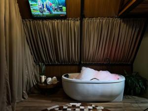 a bath tub in a bathroom with a tv at Chalé Amor & Serra in Lauro Müller