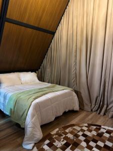 a bedroom with a bed with curtains and a checkered floor at Chalé Amor & Serra in Lauro Müller