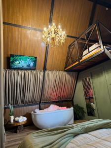 a bedroom with a bath tub and a chandelier at Chalé Amor & Serra in Lauro Müller