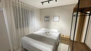 a small bedroom with a bed with white sheets at Urban Stay Botanic in Goiânia