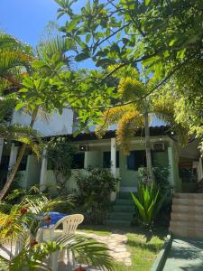 a green house with a white chair in front of it at Pousada Encanto da Ilha in Praia de Araçatiba +19 photos