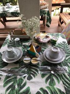 a table with plates and utensils on top of a table at Pousada Encanto da Ilha in Praia de Araçatiba