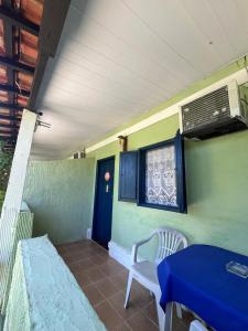 a porch with a blue door and a blue table and chair at Pousada Encanto da Ilha in Praia de Araçatiba
