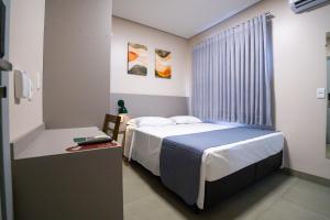 a bedroom with a bed and a table and a window at Barak Hotel in Nova Mutum