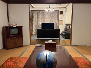 a living room with a television and a table at Lodging House NAO in Aomori