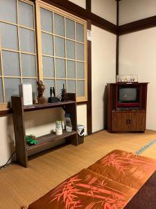a living room with a tv and a table at Lodging House NAO in Aomori