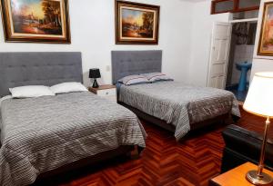 a bedroom with two beds and a lamp at Hospedaje Paris in Cusco