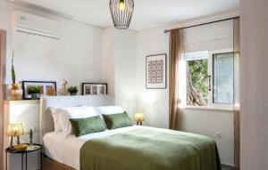 a bedroom with a bed with a green comforter and a window at Prinos 3 in Agia Galini