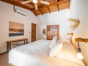 a bedroom with a white bed and a desk at Beach Heaven in Playa Guiones +22 photos