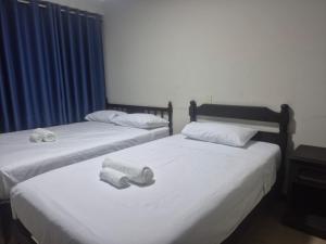 two beds with white sheets and towels on them in a room at Hotel Naciones Unidas in Lima