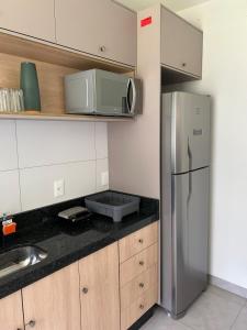 a kitchen with a stainless steel refrigerator and a microwave at Apartamento confortável, calmo e bem localizado in Lucas do Rio Verde