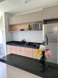 a kitchen with a black counter top and a refrigerator at Apartamento confortável, calmo e bem localizado in Lucas do Rio Verde +11 photos