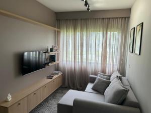 a living room with a couch and a flat screen tv at Apartamento confortável, calmo e bem localizado in Lucas do Rio Verde