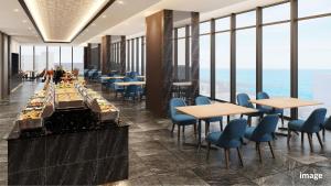 a restaurant with tables and chairs and the ocean at Village Atami in Atami