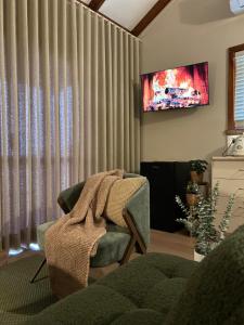 a living room with a chair and a television at 12 apostles cottages in Princetown +24 photos