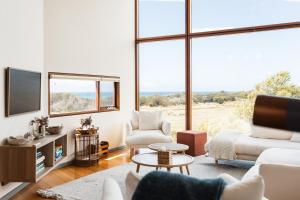 a living room with white furniture and large windows at Miramar Beach House in Seymour