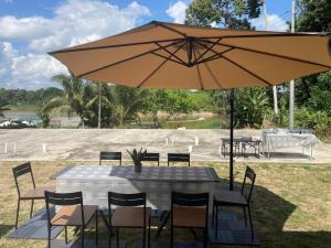 a table and chairs with an umbrella in a field at Casadana Riverview in Kampong Gemuroh +12 photos