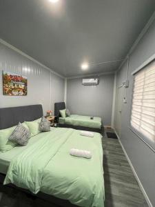 a bedroom with two beds with green sheets and a window at Casadana Riverview in Kampong Gemuroh