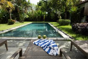 a swimming pool with a blanket and two fruits on a table at Bali Mynah Villas, Balangan Beach in Jimbaran