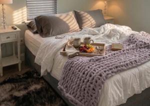 a white bed with a tray of fruit on it at Tiny Home in Town-Hot Tub - Privacy Fence - Fire Pit - Kids Play Area & 15 minutes to the Bogue Chitto State Park in Franklinton