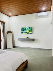 a bedroom with a bed and a tv on the wall at Sedana Pertiwi House in Ubud
