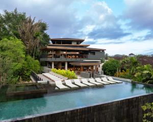 a house with a swimming pool and lounge chairs at Alaya Suites Ubud in Ubud