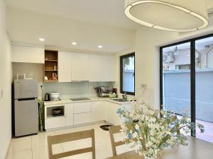 a kitchen with white cabinets and a table with a vase of flowers at Resort royal lotus Ha Long in Ha Long