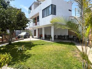 a white house with a yard in front of it at Estadía San Vicente in San Vicente de Cañete