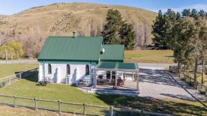 a small white house with a green roof in a field at The Church Millers Flat in Millers Flat +20 photos