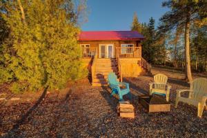 a cabin in the woods with chairs and a house at Le Huard - Lakefront & Private Dock in Sayabec