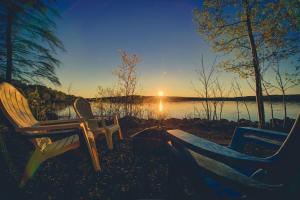 two chairs and a bench in front of a lake at Le Huard - Lakefront & Private Dock in Sayabec