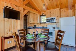 a dining room with a table with chairs and a refrigerator at Le Huard - Lakefront & Private Dock in Sayabec