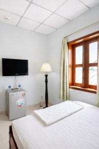 a bedroom with a bed and a tv and a window at Lina Hotel Hồ Chí Minh in Dĩ An