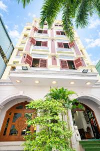 a tall pink building with a tree in front of it at Lina Hotel Hồ Chí Minh in Dĩ An +40 photos