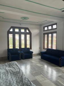 a living room with two blue couches and windows at Aura house in Jorhat