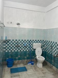 a bathroom with a toilet and a tiled wall at Aura house in Jorhat