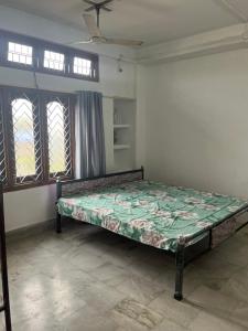 a bedroom with a bed in a room with windows at Aura house in Jorhat